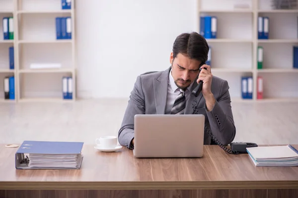 Junge attraktive männliche Mitarbeiter sitzen am Arbeitsplatz — Stockfoto