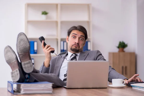 Junge attraktive männliche Mitarbeiter sitzen am Arbeitsplatz — Stockfoto