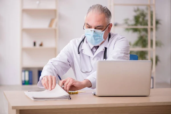 Médico do sexo masculino que trabalha na clínica durante a pandemia — Fotografia de Stock