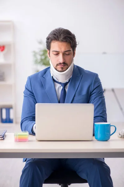 Young male employee after accident sitting at workplace — Stock Photo, Image