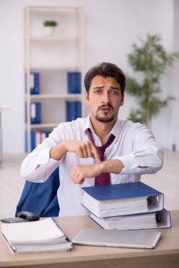 Ofisteki aşırı işten memnun olmayan genç bir erkek işçi.