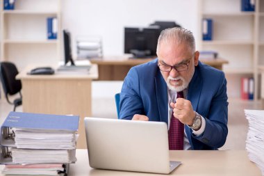 Ofisteki aşırı işten memnun olmayan yaşlı bir erkek işçi.