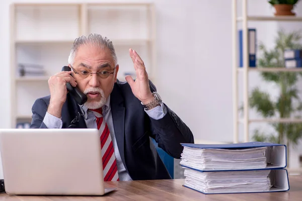 Oude mannelijke werknemer die op kantoor werkt — Stockfoto