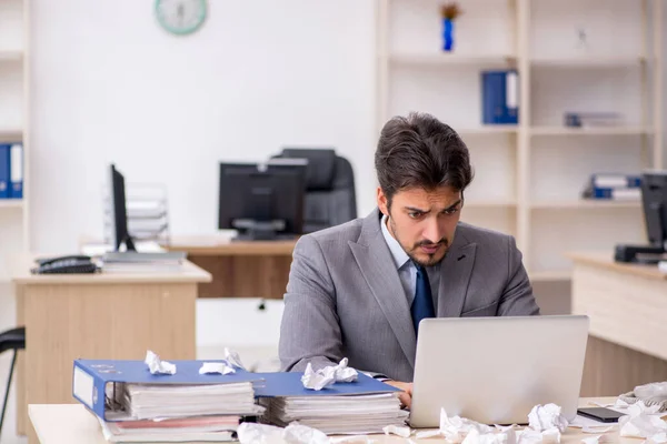 Jovem funcionário masculino e muito trabalho no escritório — Fotografia de Stock