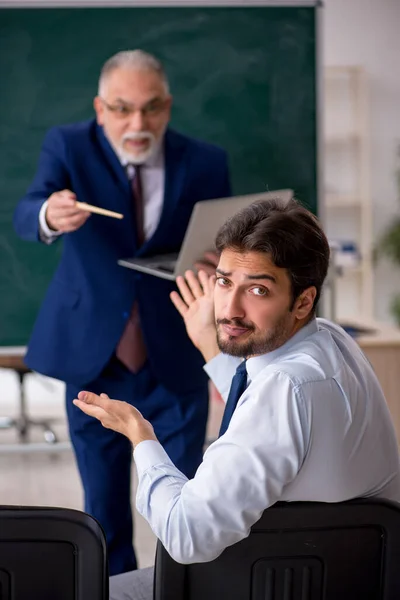 Viejo profesor masculino y joven estudiante masculino delante del tablero verde — Foto de Stock