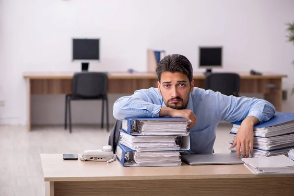 Jovem funcionário masculino e muito trabalho no escritório — Fotografia de Stock