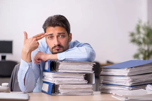 Jovem funcionário masculino e muito trabalho no escritório — Fotografia de Stock