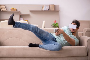 Evde sanal gözlük takan genç bir öğrenci.