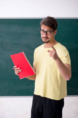 Tahtanın önünde genç bir erkek öğrenci.