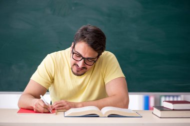 Tahtanın önünde genç bir erkek öğrenci.