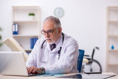 Hastanede çalışan yaşlı erkek doktor.