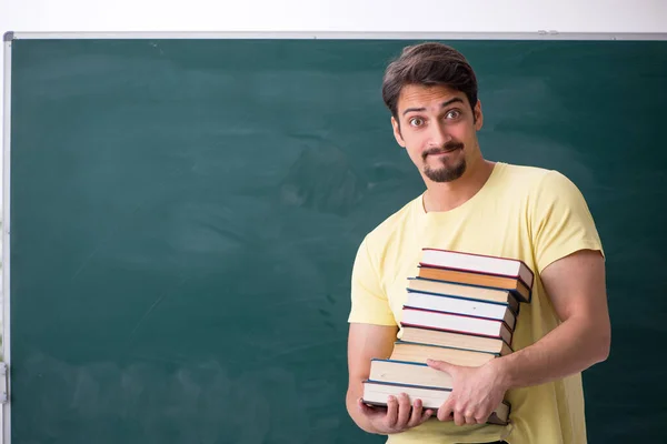 Jovem estudante do sexo masculino segurando muitos livros — Fotografia de Stock