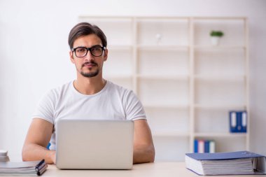 Genç erkek çalışan serbest çalışan ofiste oturuyor.