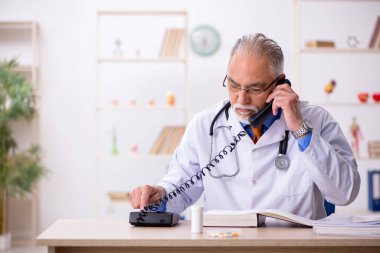 Klinikte çalışan yaşlı erkek doktor.
