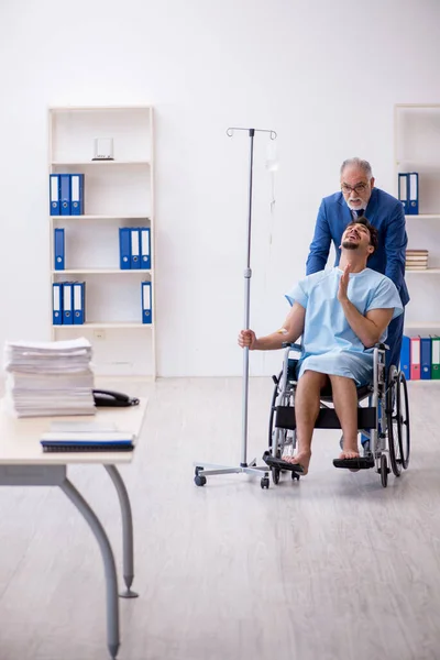 Jonge mannelijke werknemer in rolstoel voelt zich slecht op de werkplek — Stockfoto