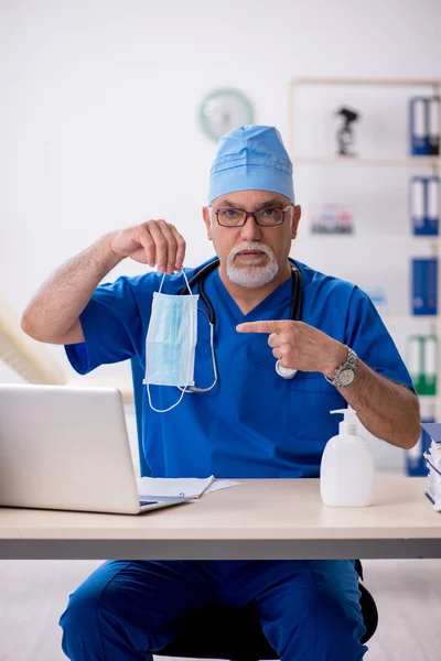 Starý lékař pracuje na klinice během pandemie — Stock fotografie