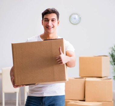 Genç adam evde kutuları taşıyor.