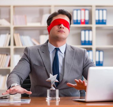 Ofiste masasında oturan gözü bağlı iş adamı.