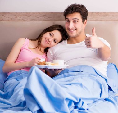Mutlu bir aile yatakta kahvaltı yapıyor.