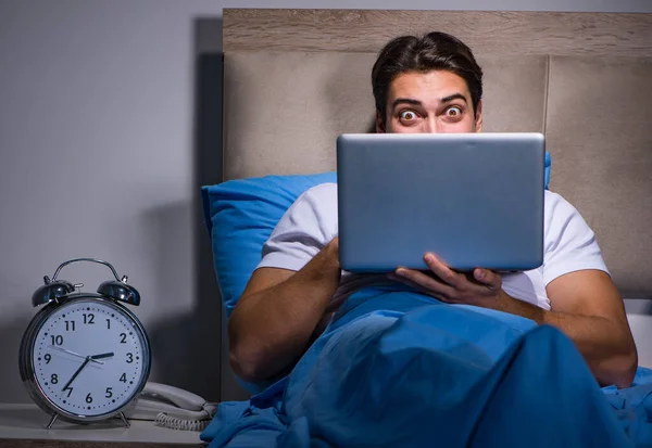 Jovem trabalhando no laptop na cama — Fotografia de Stock