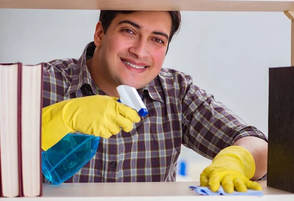 Hombre limpiando polvo de la estantería — Foto de Stock