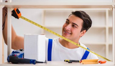 İşçi adam montaj kitaplığını tamir ediyor