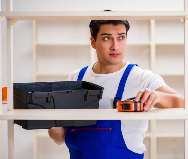 Trabalhador reparando montagem estante de livros — Fotografia de Stock