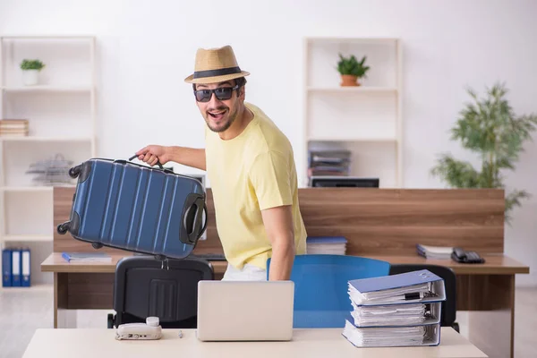 Jovem funcionário do sexo masculino se preparando para a viagem no local de trabalho — Fotografia de Stock