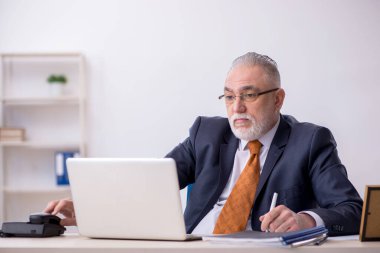 Ofiste çalışan yaşlı bir erkek.