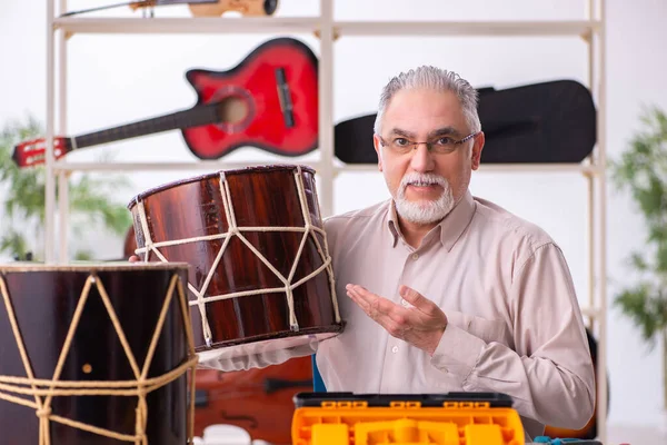 Viejo reparador masculino reparando instrumentos musicales en el lugar de trabajo —  Fotos de Stock