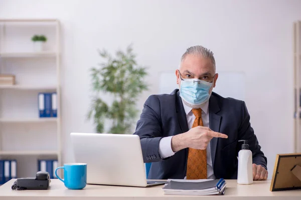 Velho funcionário do sexo masculino que trabalha no escritório durante pandemia — Fotografia de Stock