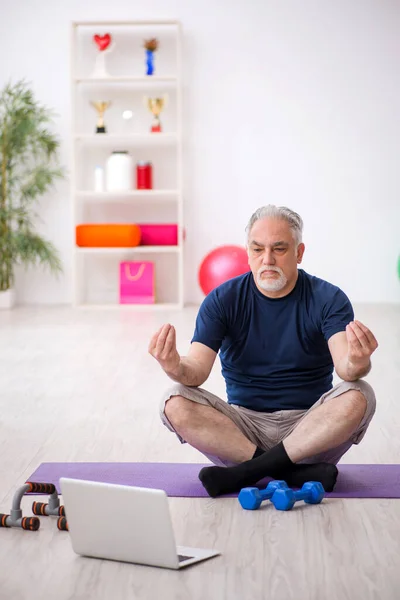 Old man doing sport exercises indoors