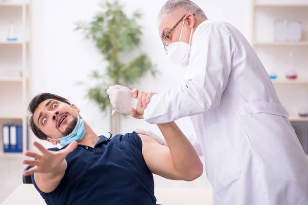 Junge männliche Patientin besucht alten Arzt im Impfpass — Stockfoto