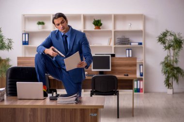 İş yerinde genç bir erkek çalışan silah tutuyor.