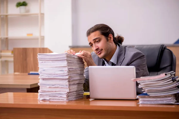 Ung manlig anställd och för mycket arbete på kontoret — Stockfoto