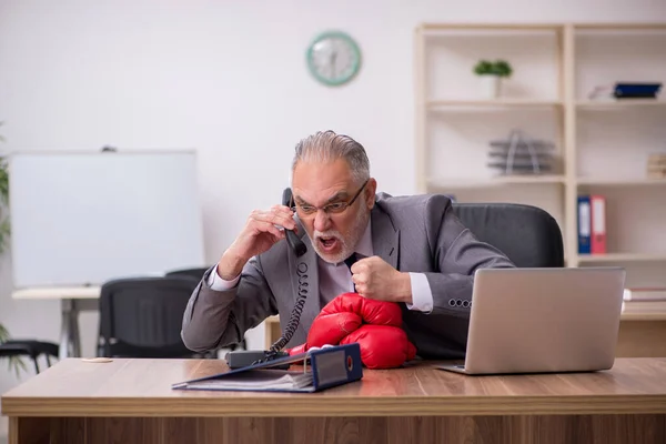 Oude zakenman draagt bokshandschoenen op het werk — Stockfoto