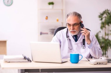 Klinikte çalışan yaşlı erkek doktor.