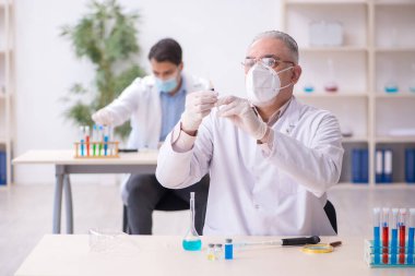 Salgın sırasında laboratuvarda çalışan iki erkek kimyager.
