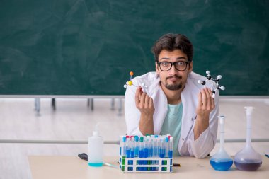 Tahtanın önündeki genç erkek kimyager.