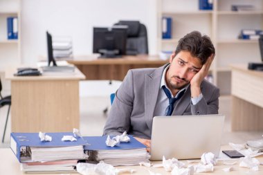 Genç bir erkek çalışan ve ofiste çok fazla iş var.