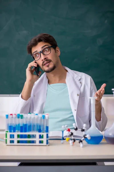 Jovem químico masculino na frente do quadro negro — Fotografia de Stock