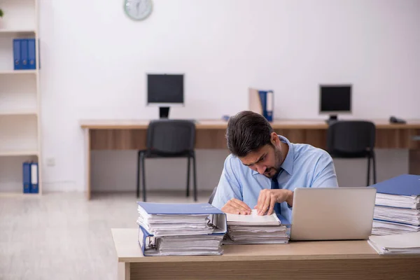 Ung manlig anställd och för mycket arbete på kontoret — Stockfoto