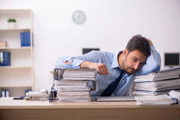 Młody pracownik płci męskiej i zbyt dużo pracy w biurze — Zdjęcie stockowe