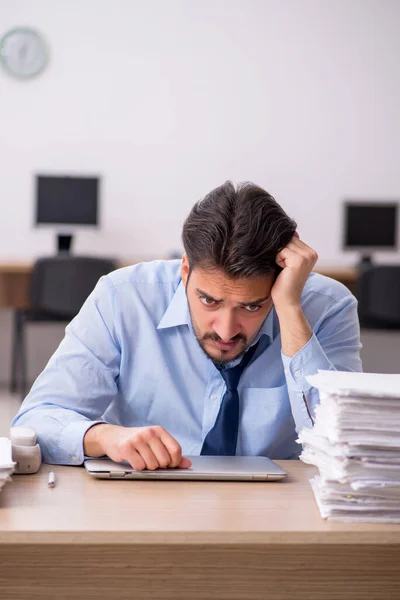 Junge männliche Mitarbeiter und zu viel Arbeit im Büro — Stockfoto