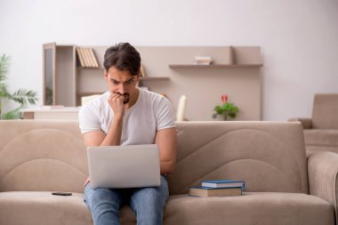 Genç erkek öğrenci salgın sırasında evde çalışıyor.