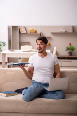 Genç erkek öğrenci salgın sırasında evde çalışıyor.