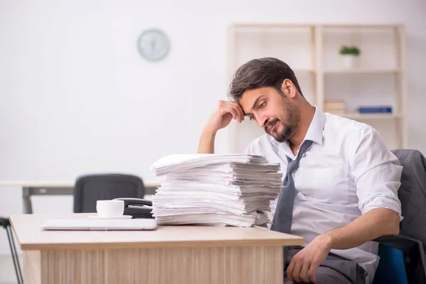 Joven empleado masculino y demasiado trabajo en la oficina — Foto de Stock
