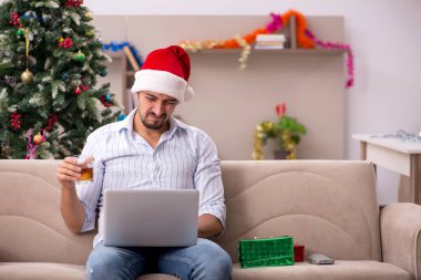 Genç adam Noel 'i evde yalnız kutluyor.