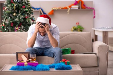 Genç adam Noel 'i evde yalnız kutluyor.