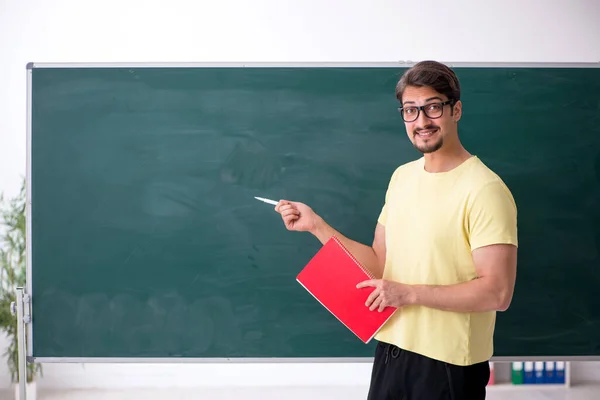 Jovem estudante do sexo masculino na frente do quadro negro — Fotografia de Stock